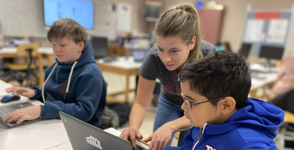 Teacher working with students on laptops