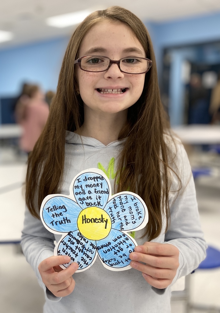 student holding paper flower with word honesty